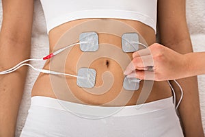 Therapist placing electrodes on woman's stomach