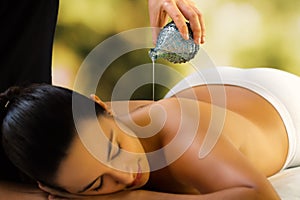 Therapist pouring massage oil on woman`s back.