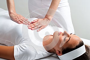 Therapist pressing with hands on womans chest at reiki session. photo