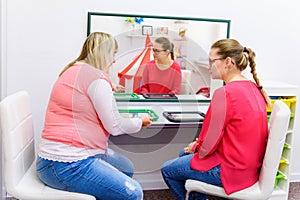 Therapist teaching young mother of a non-verbal child how to use speech-generating device. photo