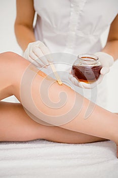 Therapist waxing womans leg at spa center