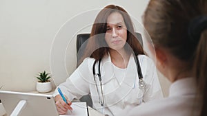 Therapist works with a sick woman. Doctor records patient's complaints. Family doctor is talking to a patient in office