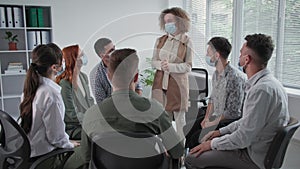 therapy sessions during quarantine, young group of people in medical masks talk about their problems and applaud each