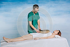 The therapy of a woman with a tambourine. Male masseur does nontraditional methods of medicine. photo