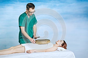 The therapy of a woman with a tambourine. Male masseur does nontraditional methods of medicine. Beautiful relaxed face photo