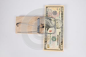 There is a 10 dollar bill in a mousetrap on white