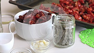 There is a baking sheet with sun-dried tomatoes on the table. Nearby spices. Cooking sun-dried tomatoes in olive oil. Close-up