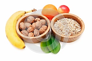 There are Banana,ApÐ·le,Orange with Walnuts in the Wooden Plate and Rolled Oats,with Green Leaves,Healthy Fresh Organic Food