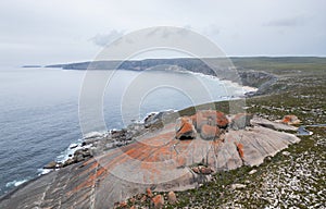 there is a big rock on the beach next to the water