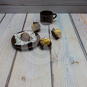 There is a brown porcelain cup and saucer on the wooden table.