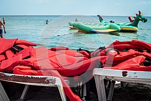 There are a bunch of life jackets on the sun loungers on the beach. Life jackets for water riding. Safety of vacationers