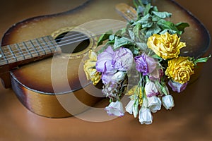 There is a bunch of roses on an old guitar.