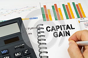 There is a calculator on the table, business charts, a man made a note in a notebook - capital gain