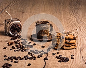 There is a coffee cup with a saucer made of coconut palm wood. From glass jar chaotically scattered roasted coffee beans