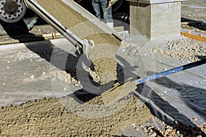 There is a concrete mixing truck in the middle of the new home pouring concrete for the pavement