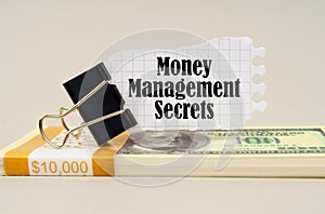There are dollars on the table, on which there is a clip and torn paper with the inscription - Money Management Secrets