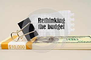 There are dollars on the table, on which there is a clip and torn paper with the inscription - Rethinking the budget