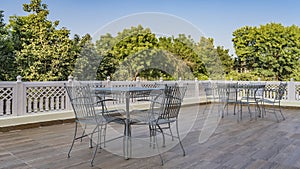 There are elegant metal chairs and tables on the outdoor terrace.