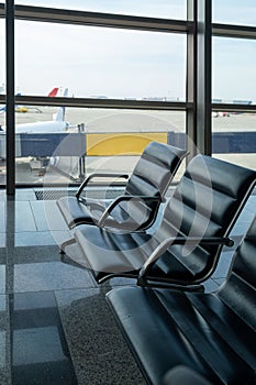 There are empty chairs, benches for passengers waiting for flights at the airport terminal, selected focus