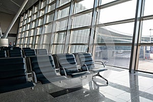 There are empty chairs, benches for passengers waiting for flights at the airport terminal, selected focus