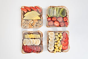 There are four sandwiches on the white surface. Bread covered with chocolate paste, strawberry and banana, mango. A sweet