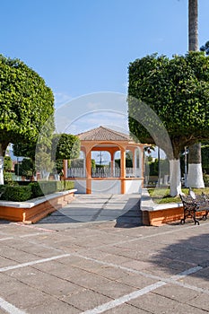 there is a gazebo with two benches and trees in the background