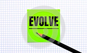 There is a green sticker with the text EVOLVE and a black pencil on the checkered paper