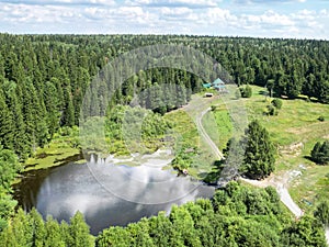 There is a house on the edge of the taiga, next to a small lake with a boat on the shore