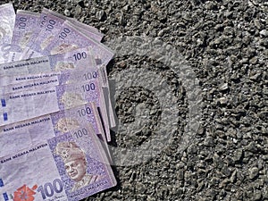 There is a hundred ringgit malaysia scattered on the road.