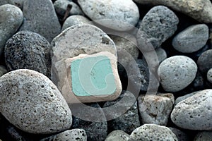 there is a light green stone among some pebbles on the beach