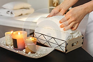 There are lit aromatic candles on the table, a spa center employee puts towels for treatments