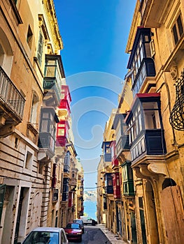 There are a lot of old buildings in the street. Blue clear sky. Facade of a house with a colored wall. Colorful facades of houses