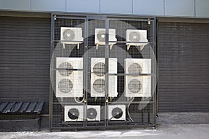 There are many working air conditioners of different types and capacities near the wall of a store or office