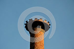 There is a metal toothed structure for the nesting of white storks on the brick historic chimney of the brewery. Brown burnt brick