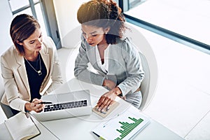 There are always new business trends to explore. two corporate businesswomen working together on a laptop in an office.