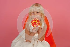 There is no resisting the sugary charms. Little child with sweet lollipop. Happy candy girl. Little girl hold lollipop