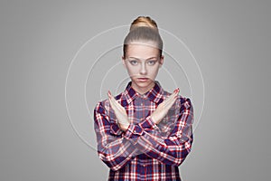 There is no way. serious beautiful blonde girl in red, pink checkered shirt, collected bun hairstyle, standing and looking at cam