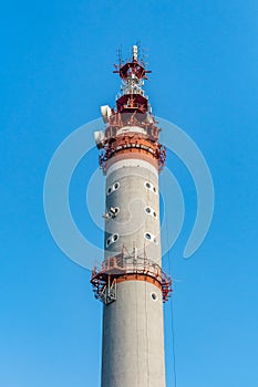 There is one gray and red Radio relay tower with group of different antennas on the blue sky background photo