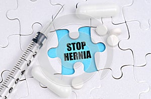 There are pills and a syringe on the white puzzles. Inside on a blue background the inscription - STOP HERNIA