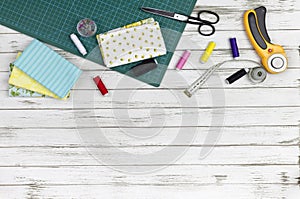 Quilting, embroidery and sewing tools on the white wooden background. patchwork knife, scissors, lined cutting mat, self-locking,