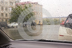 There is rainy weather outside the car window, raindrops on the glass. Bad weather and poor visibility