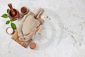 There is raw chicken on cutting board with spices.