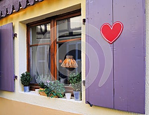 There is red painted heart on the window shutters. Concept of love.