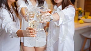 There`s toast. A group of female friends in white shirts clink glasses with champagne.