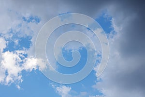A blue sky with white clouds and tree branches below
