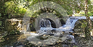 There is a small waterfall located in the peaceful middle of a forest