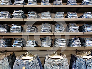 There are stacks of new jeans on the shelves of a clothing store. Retail boutiques