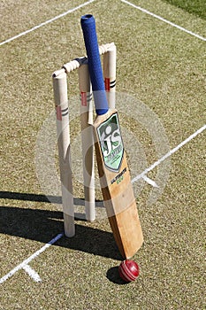 there are three cricket bats and a ball near the stump