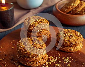 There are three small stacks of oatmeal cookies on the round kitchen board