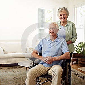 Always there to care. Portrait of a smiling senior man in a wheelchair and his wife at home.